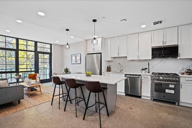 kitchen featuring appliances with stainless steel finishes, white cabinetry, backsplash, a kitchen island, and decorative light fixtures