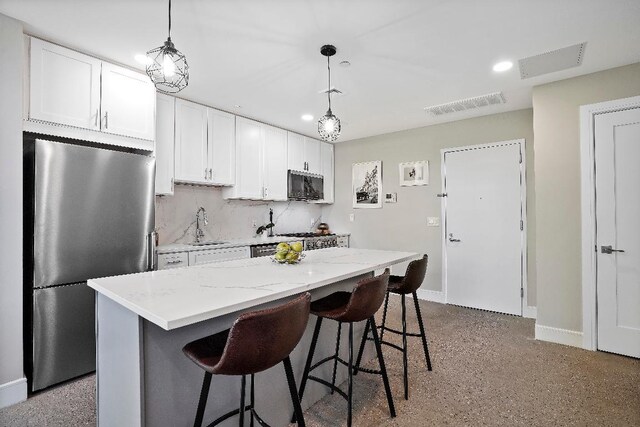 kitchen with sink, white cabinetry, decorative light fixtures, stainless steel fridge, and a kitchen island