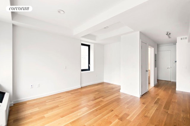 empty room with hardwood / wood-style flooring and a raised ceiling