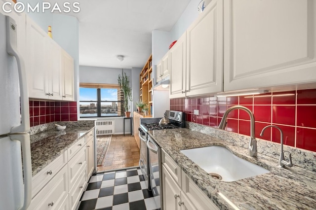 kitchen with radiator, sink, stainless steel gas stove, white refrigerator, and white cabinets