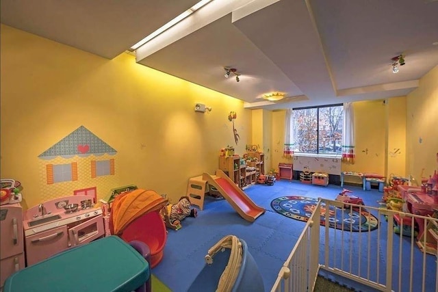 recreation room with carpet floors and rail lighting