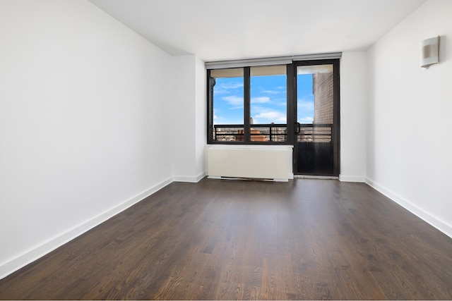 unfurnished room featuring dark wood-type flooring, radiator heating unit, and baseboards