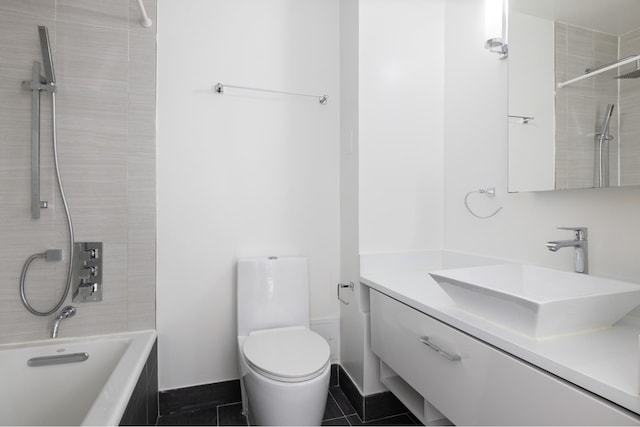 bathroom with baseboards, toilet, tiled shower / bath combo, tile patterned flooring, and vanity