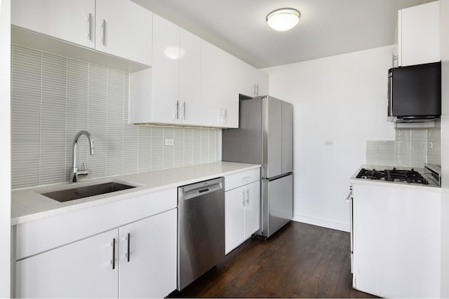 kitchen with stainless steel appliances, light countertops, decorative backsplash, dark wood-type flooring, and a sink