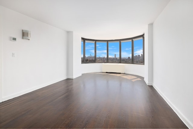 unfurnished room featuring radiator, baseboards, and wood finished floors