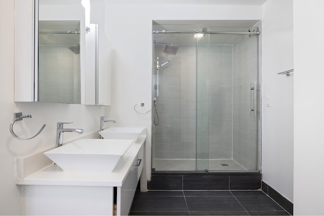 bathroom with double vanity, tile patterned flooring, a sink, and a shower stall