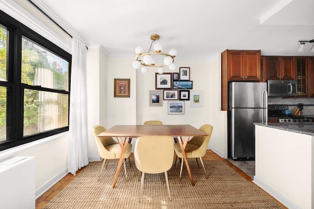 dining area with a notable chandelier, crown molding, and light hardwood / wood-style floors