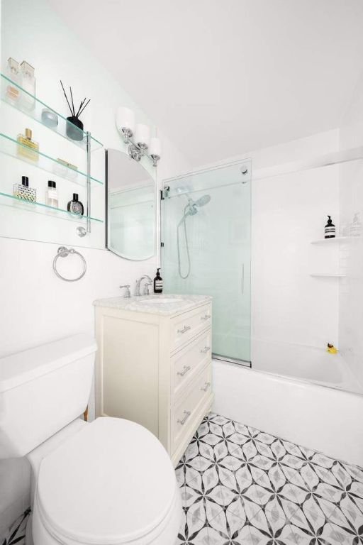 full bathroom with combined bath / shower with glass door, vanity, and toilet