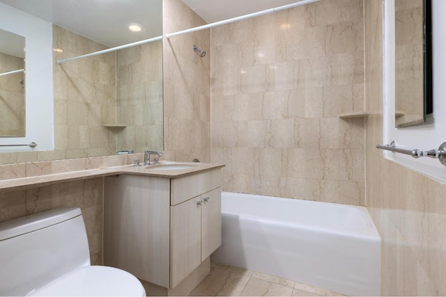 full bathroom with tile patterned floors, toilet, tiled shower / bath, tile walls, and vanity