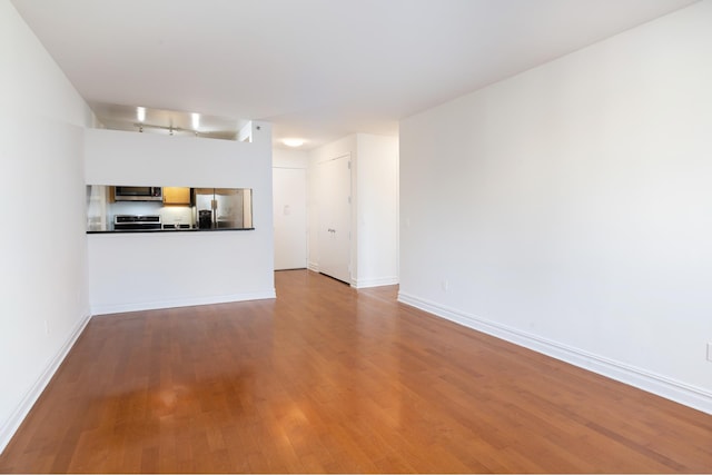 unfurnished living room with baseboards and wood finished floors