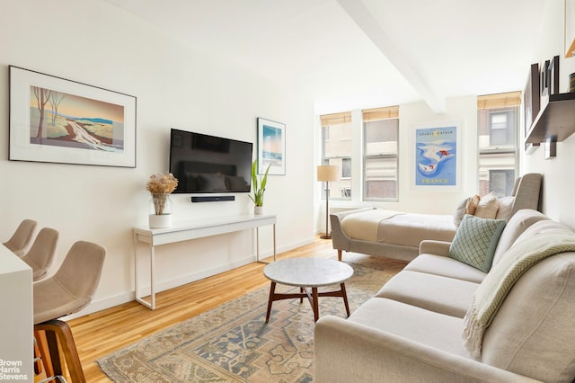 living room featuring baseboards, beamed ceiling, and wood finished floors