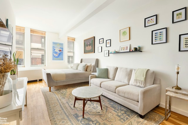 bedroom with light wood-type flooring, beam ceiling, and baseboards