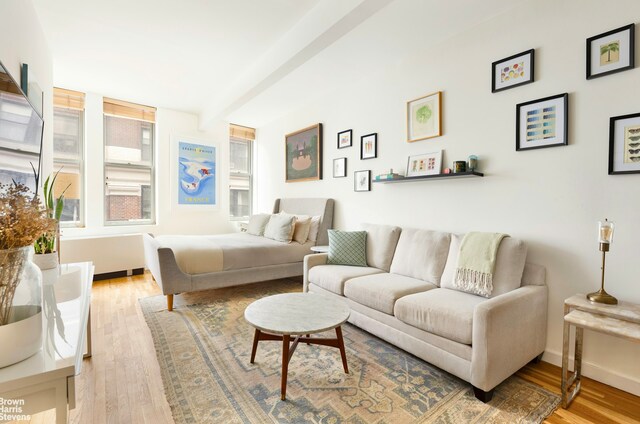 bedroom with light wood finished floors, beamed ceiling, and baseboards