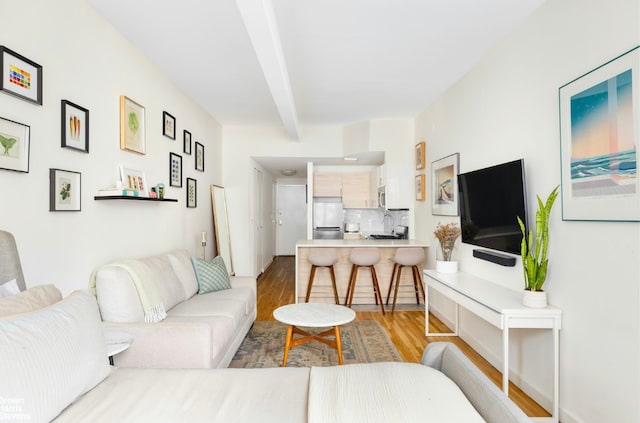 living room with beamed ceiling, wood-type flooring, and sink