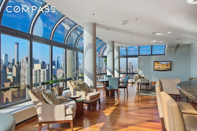 living area with visible vents, a view of city, wood finished floors, and floor to ceiling windows