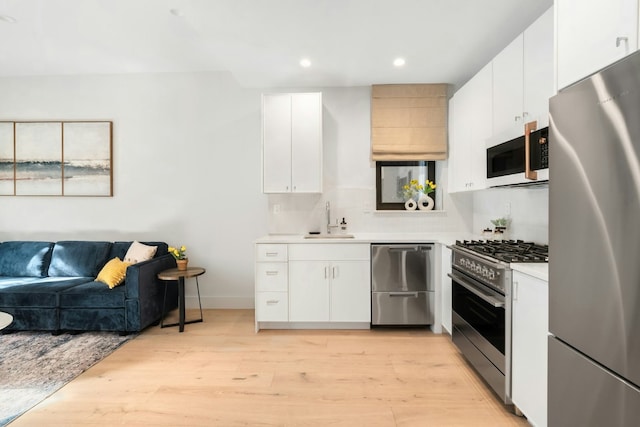 kitchen featuring sink, stainless steel appliances, white cabinets, and light wood-type flooring