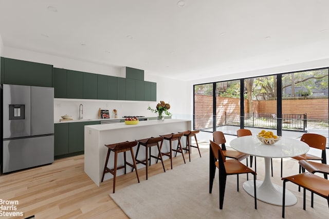 dining area with sink, a wall of windows, and light wood-type flooring