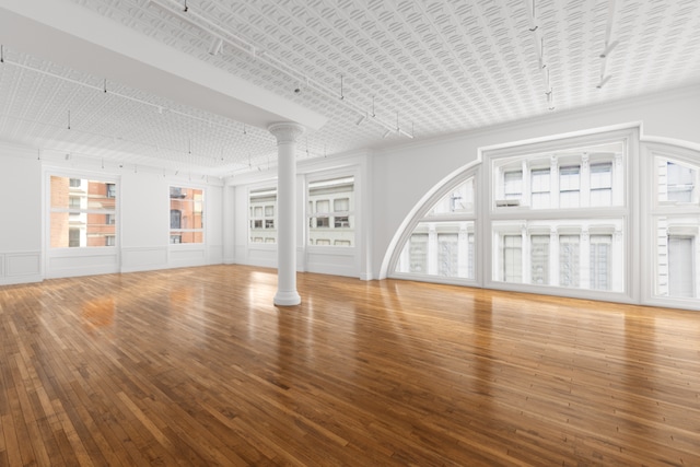 unfurnished living room with decorative columns and hardwood / wood-style floors