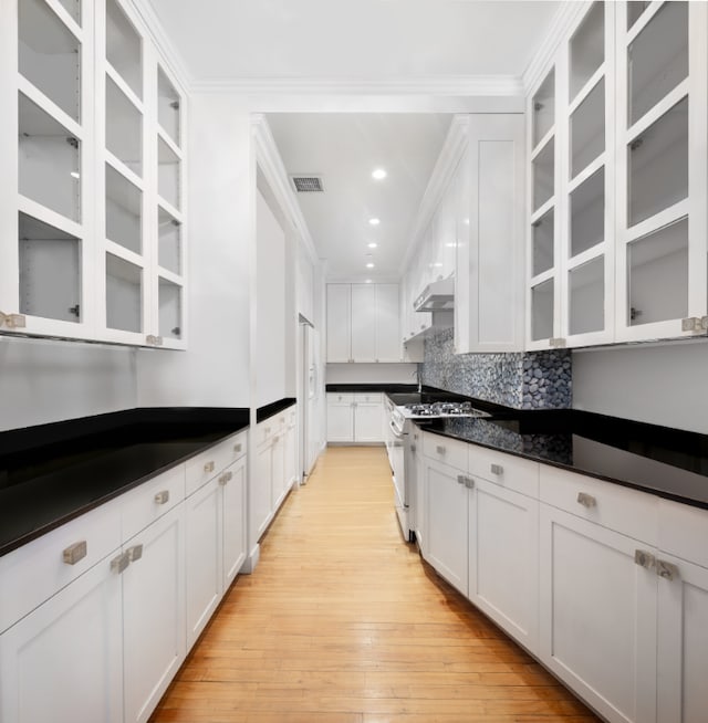 kitchen with white cabinetry, dark stone countertops, light wood-type flooring, white appliances, and backsplash