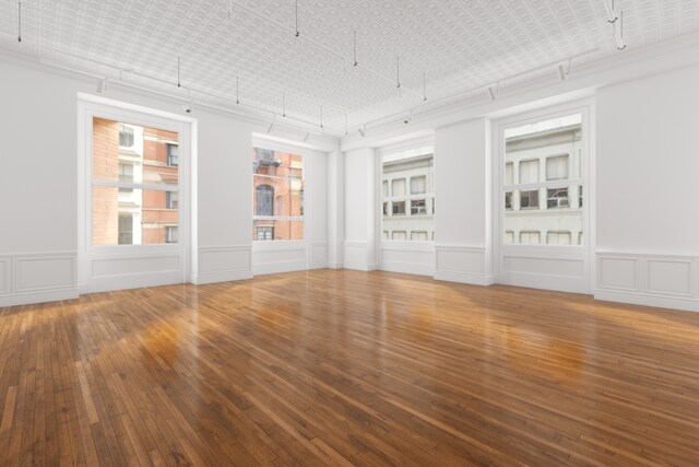 basement featuring rail lighting and hardwood / wood-style floors