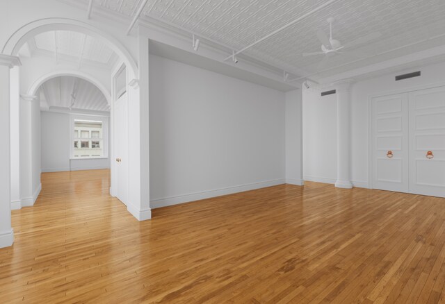 unfurnished living room featuring hardwood / wood-style flooring and ornate columns