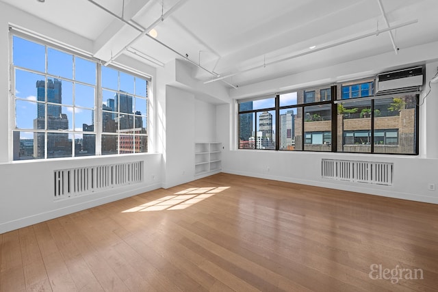 empty room featuring hardwood / wood-style flooring, a view of city, visible vents, and a wall mounted AC