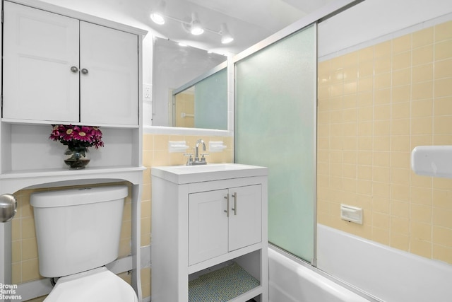 bathroom with bath / shower combo with glass door, vanity, and toilet