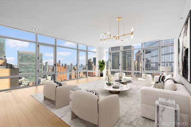 living room with light hardwood / wood-style floors, an inviting chandelier, and expansive windows