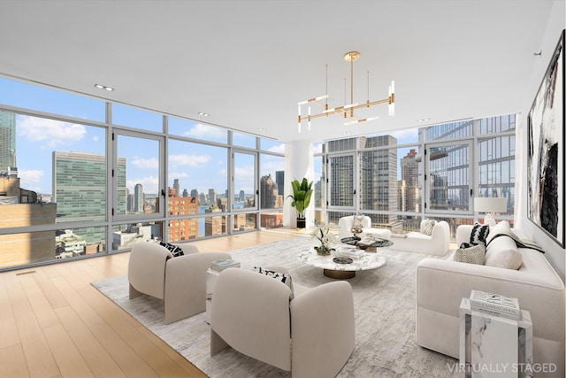 living room featuring a view of skyline, a wall of windows, a chandelier, and wood finished floors