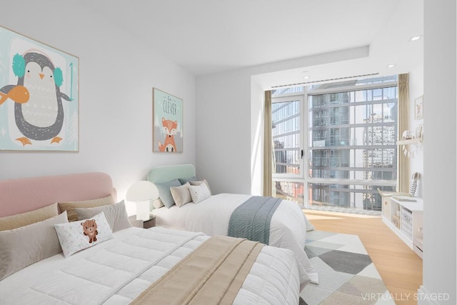 bedroom featuring light wood-type flooring and floor to ceiling windows