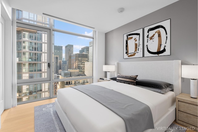 bedroom featuring expansive windows, wood finished floors, and a city view
