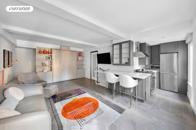 living area featuring beamed ceiling, visible vents, and light wood finished floors