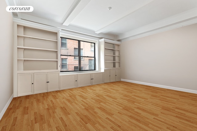 empty room with light wood finished floors, beamed ceiling, visible vents, and baseboards