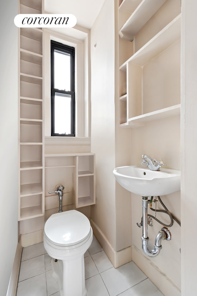 half bath with tile patterned flooring, toilet, and baseboards