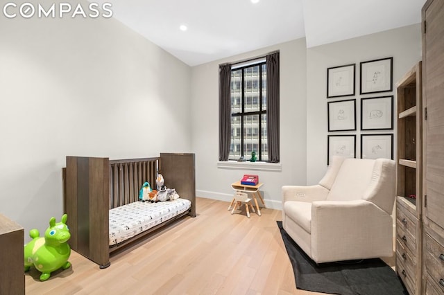 bedroom featuring a nursery area and light hardwood / wood-style flooring