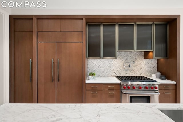 kitchen with premium range, backsplash, and light stone counters