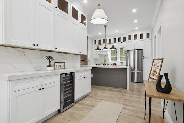 kitchen featuring pendant lighting, stainless steel refrigerator, white cabinetry, backsplash, and wine cooler