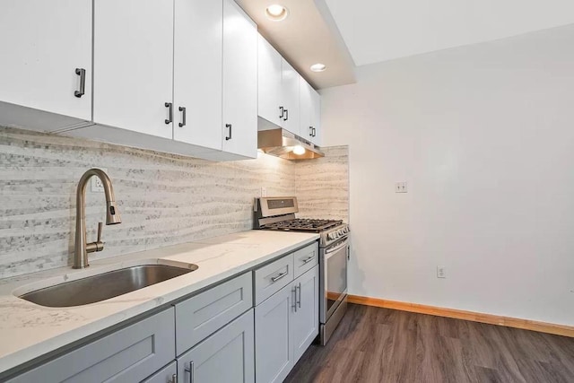 kitchen with stainless steel gas range oven, light stone counters, under cabinet range hood, a sink, and white cabinetry