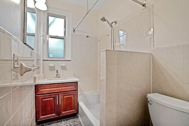 full bath featuring toilet, shower / washtub combination, vanity, and tile walls