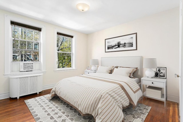 bedroom featuring cooling unit, radiator heating unit, baseboards, and dark wood-style flooring