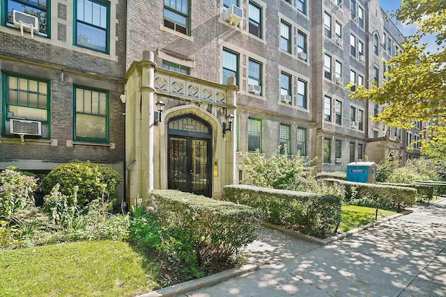 view of exterior entry with french doors, brick siding, and cooling unit