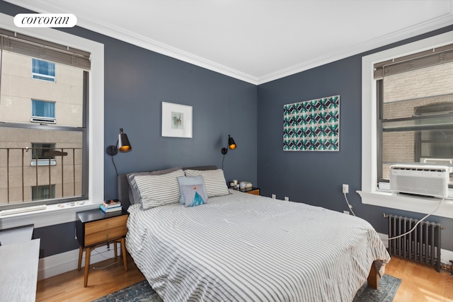 bedroom with radiator, wood finished floors, crown molding, baseboards, and cooling unit