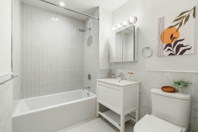 full bathroom with tiled shower / bath, vanity, toilet, and tile walls