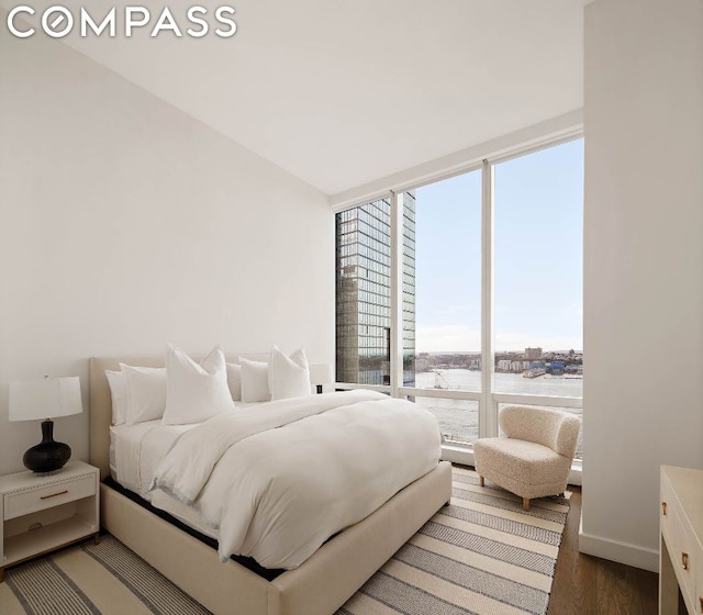 bedroom with floor to ceiling windows and dark hardwood / wood-style flooring