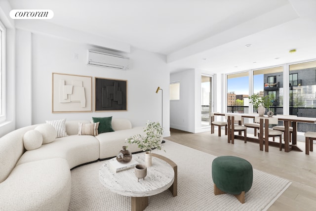 living room with a wall of windows, light hardwood / wood-style flooring, and a wall mounted air conditioner