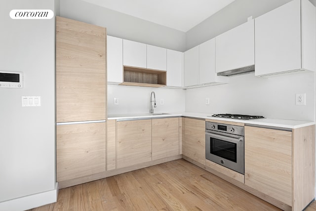 kitchen featuring sink, white cabinetry, stainless steel appliances, and light wood-type flooring