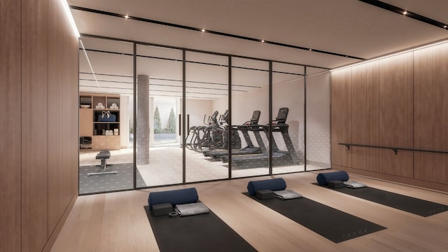 exercise room with wooden walls and light wood-type flooring