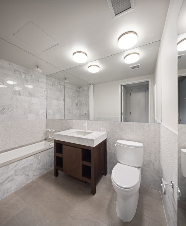 full bathroom featuring toilet, tile walls, and tiled shower / bath combo