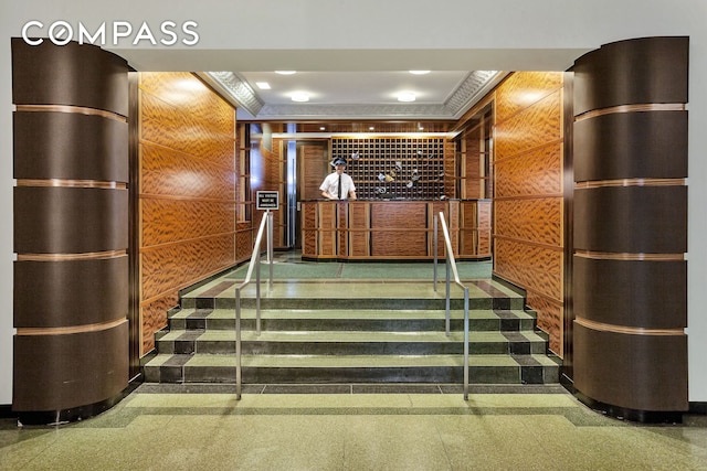 staircase featuring elevator, granite finish floor, and wood walls