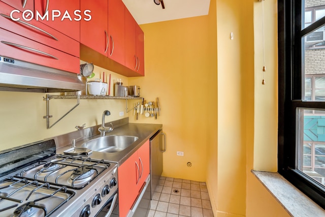 kitchen with under cabinet range hood, a sink, stainless steel appliances, red cabinets, and light tile patterned flooring